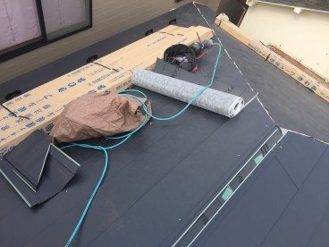 屋根に防水紙を敷き込む作業